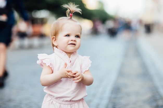 Free photo portrait of little, cute, beautiful girl walks through the city in pink dress.