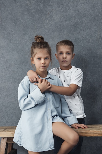 Free photo a portrait of little girl and a boy on the gray wall