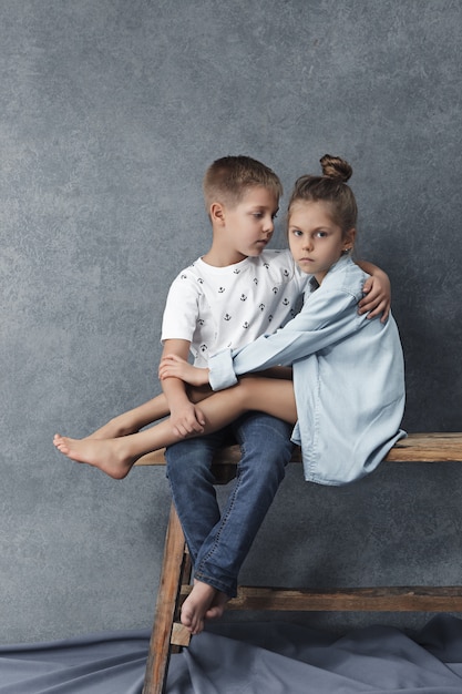 A portrait of little girl and a boy on the gray