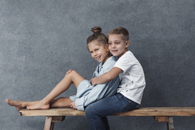 Free photo a portrait of little girl and a boy on the gray