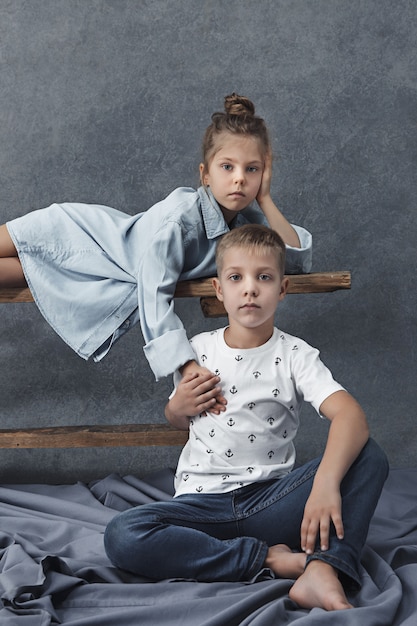 A portrait of little girl and a boy on the gray