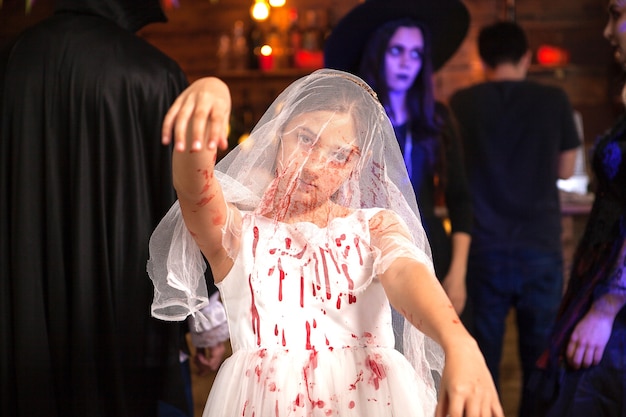 Free Photo portrait of little girl dressed up like a bride covered with blood at halloween party. girl with creepy expression.