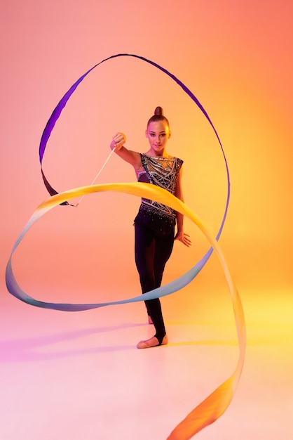 Portrait of little girl, rhythmic gymnastics artist training isolated on colored