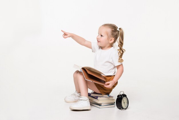 Portrait of a little girl sitting on a stack of books..