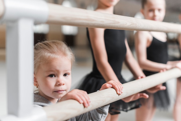 Portrait of little girl with ballerians standing near the wooden bar