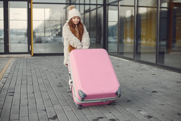 Portrait of a little girl with luggage going to airport terminal