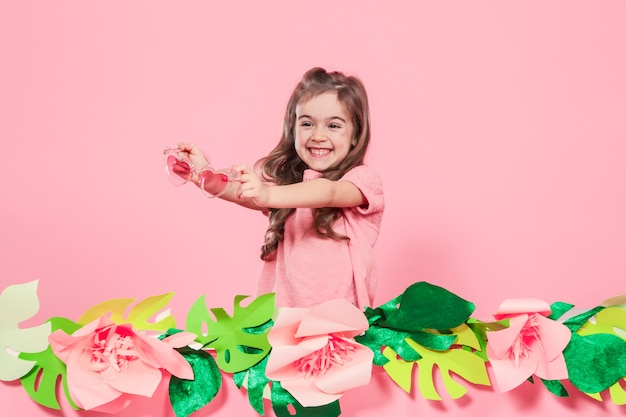 Free photo portrait of a little girl with sunglasses on a pink background