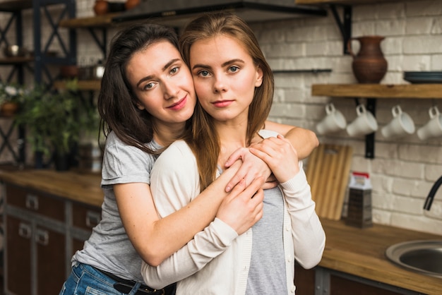 Free photo portrait of a lovely lesbian young couple standing in the kitchen