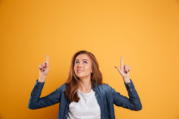 Portrait of a lovely smiling girl pointing two fingers up