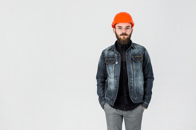 Portrait of a male architect wearing hardhat standing against white backdrop