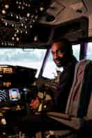 Free photo portrait of male aviator sitting in airplane cockpit ready to fly, using control panel navigation and dashboard command buttons. pilot flying aircraft with windscreen compass and radar.