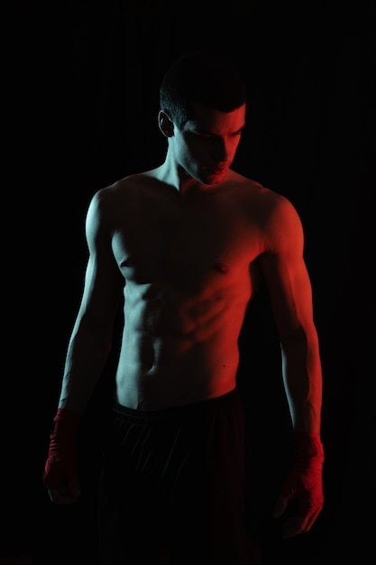 Portrait of male boxer posing in red and white light