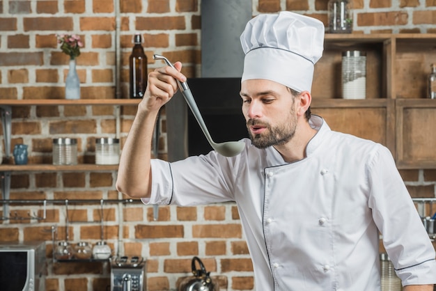 Free Photo portrait of male chef tasting soup in ladle