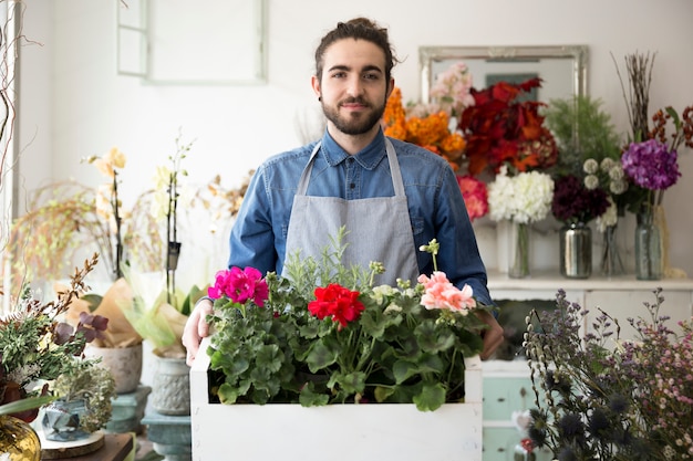 Free photo portrait of a male florist holding the colorful hydrangea flowers in crate