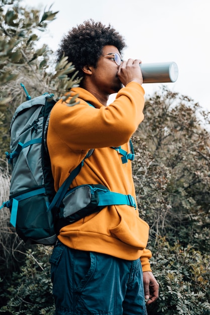 Free photo portrait of a male hiker with his backpack drinking the water from bottle