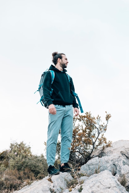 Portrait of a male hiker with his backpack standing on rocky mountain