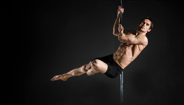 Portrait of male model performing a pole dance