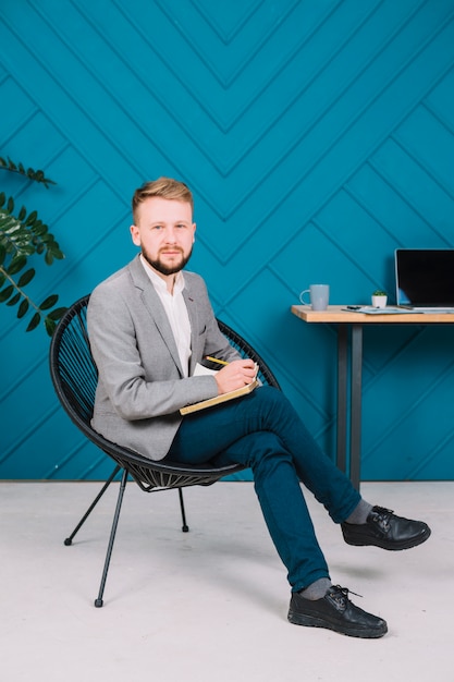 Free photo portrait of a male psychologist writing note on diary with pencil