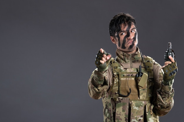 Free Photo portrait of male soldier in camouflage with grenade on dark wall