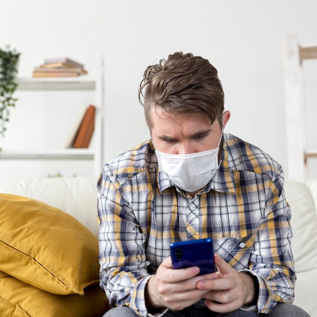 Portrait of male with face mask browsing mobile phone