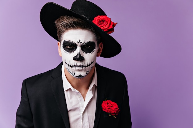 Portrait of man in frightening Mexican style mask looking sternly at camera.