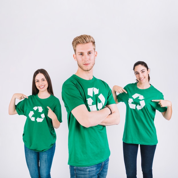 Free photo portrait of a man in front of his female friends showing recycle icon on their green t-shirt