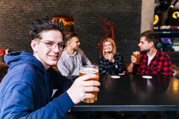 Portrait of a man holding the glass of beer sitting with friends