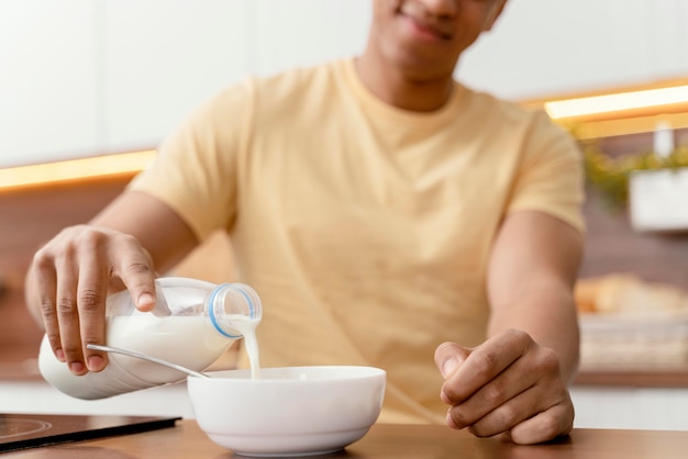 Free Photo portrait man at home pouring milk in bowl