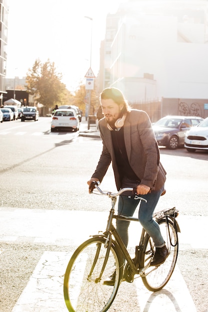 Portrait of a man riding bicycle on city road in sunlight