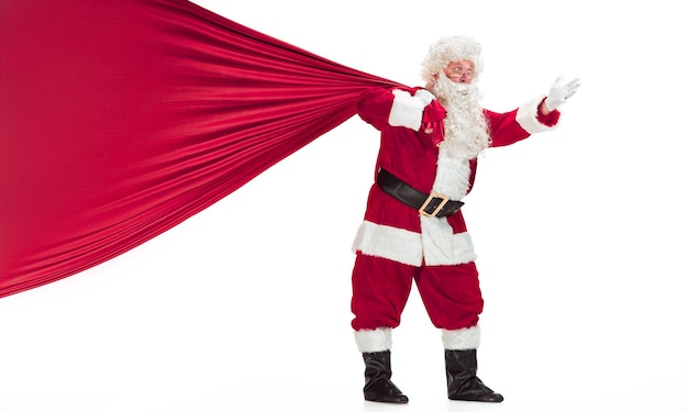 Free Photo portrait of man in santa claus costume - with a luxurious white beard, santa's hat and a red costume - in full length isolated on a white background with big bag of gifts