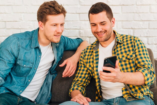 Portrait of a man showing something to his friend on smartphone