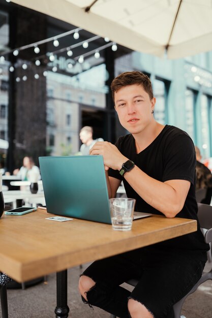 Portrait of man sitting at a table working on a laptop computer.