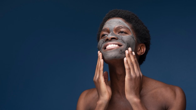 Portrait of a man smiling with charcoal mask on his face