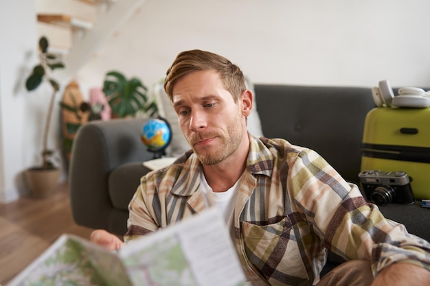 Free photo portrait of man traveller looks confused at map studying the route to go on vacation or business