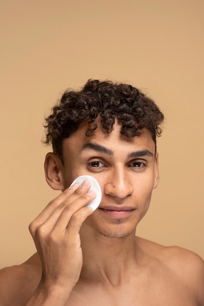 Portrait of a man wiping his face with a make-up pad