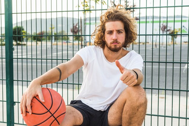 Portrait of a man with basketball gesturing thumb up