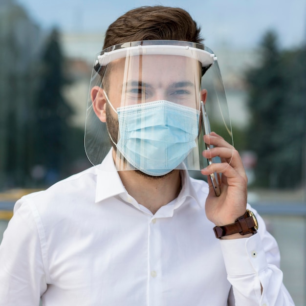 Portrait man with mask talking over phone