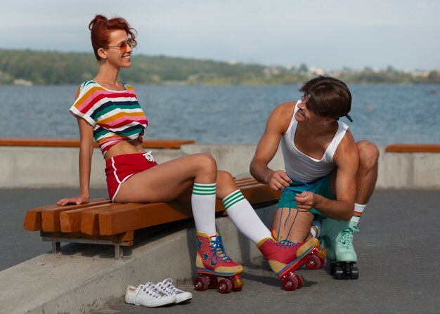 Portrait of man and woman at the beach with roller skates in 80's aesthetic