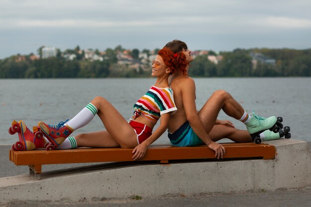 Portrait of man and woman at the beach with roller skates in 80's aesthetic