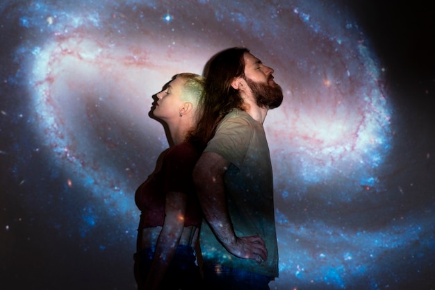 Portrait of man and woman posing with universe projection texture