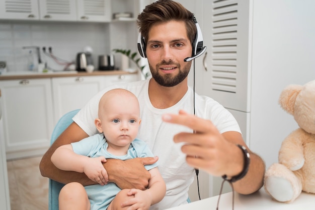 Portrait of man working while holding baby