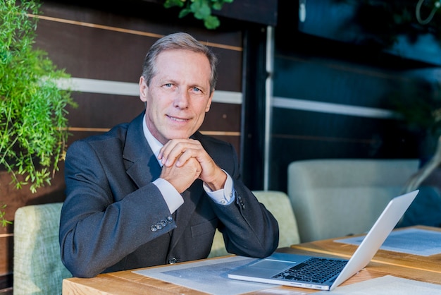 Portrait of a mature businessman with laptop over desk in restaurant