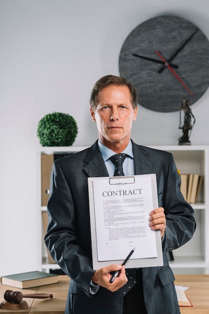 Free Photo portrait of mature lawyer showing legal contract agreement in the courtroom