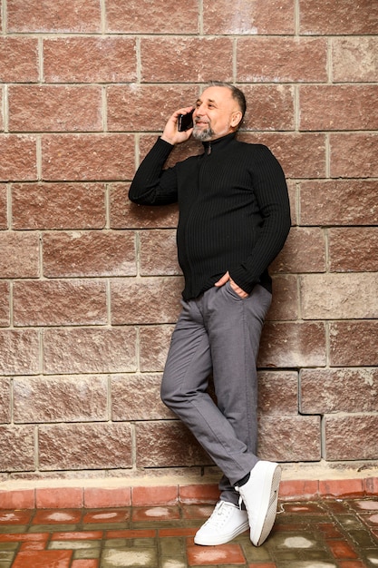 Portrait of mature man standing next to brick wall