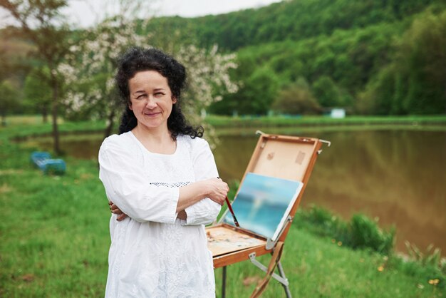 Portrait of mature painter with black curly hair in the park outdoors