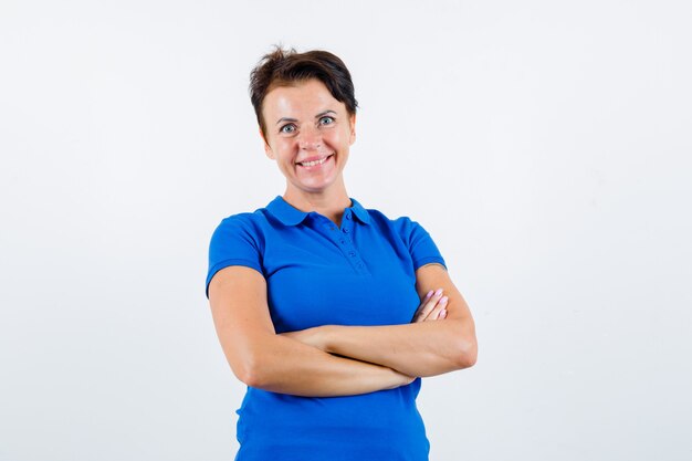 Portrait of mature woman standing with crossed arms in blue t-shirt and looking confident front view