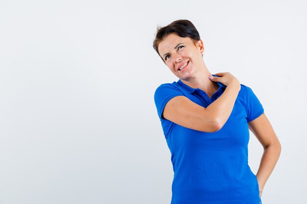 Portrait of mature woman suffering from neck pain in blue t-shirt and looking tired front view