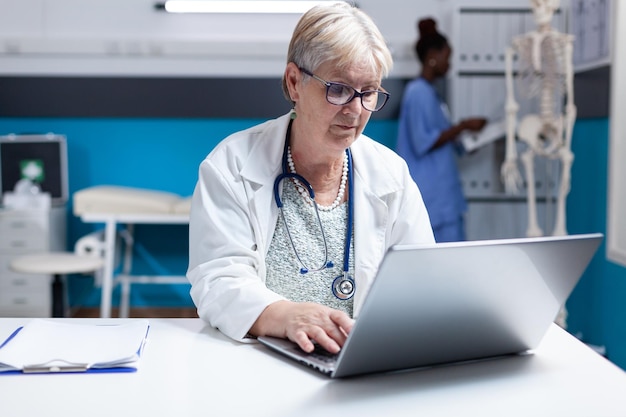 Portrait of medic with stethoscope using laptop to work on healthcare in cabinet. Woman doctor working with computer and technology to do prescription treatment analysis for examination.