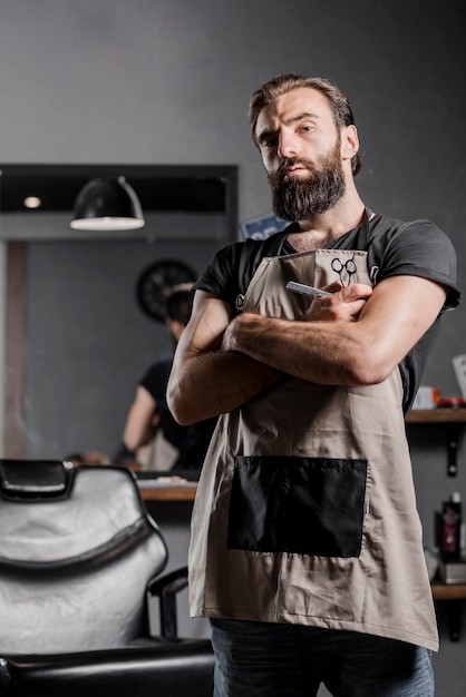 Portrait of a mid adult bearded male barber with folded arms