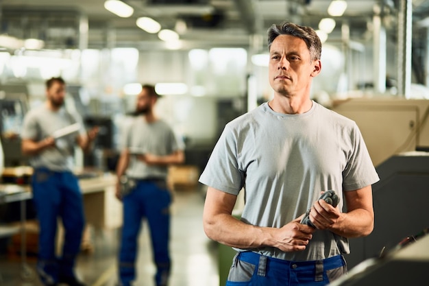 Portrait of mid adult CNC operator looking away while standing in a factory